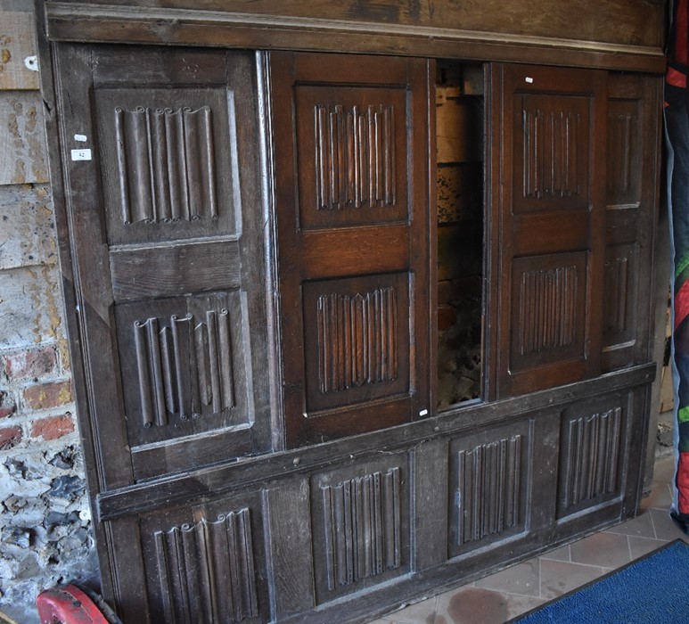 A large linenfold carved oak panel with sliding doors