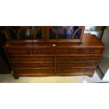 A crossbanded yew wood sideboard with arrangement of nine drawers raised on bracket feet