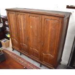 Large oak provincial linen cupboard with four full length panelled doors enclosing hanging rail