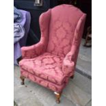 A Georgian style wingback arm chair with burgundy damask upholstery