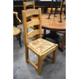 A set of four solid oak ladder back dining chairs with rush work pad seats, square supports and