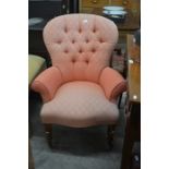 An Edwardian button upholstered spoon back armchair upholstered in salmon pink