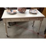 Cream painted desk with two frieze drawers raised on turned legs with brass castors