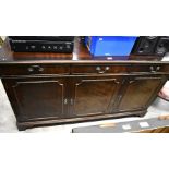 A mahogany sideboard with three drawers over panelled cupboard doors raised on bracket feet