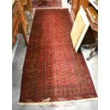 A Persian Turkaman runner with three rows of repeating guls on red ground within a guarded border