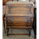 A panelled oak fall front bureau with fitted interior over two long drawers raised on braley twist