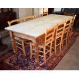 An old pine kitchen dining table with rectangular top raised on a stained base with turned legs