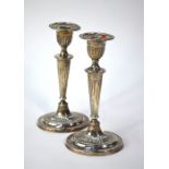 A pair of Edwardian loaded silver oval candlesticks in the Adam style with fluted decoration,