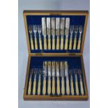 A set of twelve each electroplated dessert knives and forks with engraved blades and carved ivory