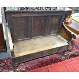 An 18th century oak settle, the triple panelled back with moulded beading, the swept arms over a