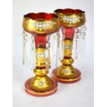 A pair of Venetian cranberry and gilt vases hung with prism lustre drops, floral encrusted