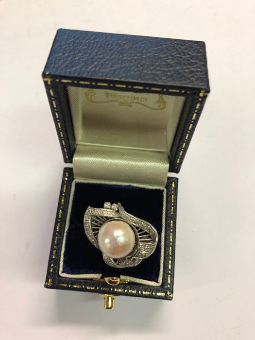 A white metal cluster ring, the central large cultured pearl with closed back and ornate scroll