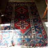 A Turkish geometric design rug with triple central medallion on red and  navy ground within