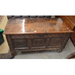 A 19th century oak coffer with hinged top over a heavily carved triple panel front raised on stile