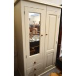 A cream painted compactum wardrobe with panelled and mirrored doors and three fitted drawers