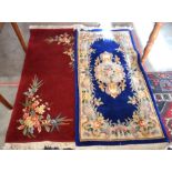 A Peking style red ground wool rug with floral decoration to/w a floral blue ground rug (2)