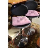 A pair of black leatherette and stainless adjustable breakfast bar stools