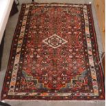 A Persian Hamadan rug with central ivory lozenge and mina khani design on red ground within