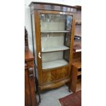 A mahogany bow front display cabinet with glazed and panelled doors enclosing shelves, raised on