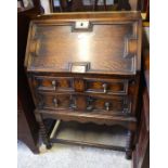 A Jacobean style oak bureau with two drawers and bobbin turned supports united by stretchers