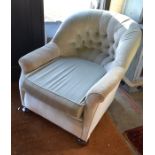A pale blue upholstered button back armchair with bun feet