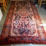 A Persian Hamadan kelleigh rug with stylised designs on a dark ground within red border with