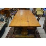 A stained pine refectory table with rectangular top on trestle supports united by stretchers