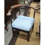 An oak library corner chair with caned seat and blue cushion with repeating pineapple pattern,
