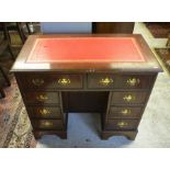 A mahogany kneehole desk with gilt tooled red leather top over eight drawers and central niche