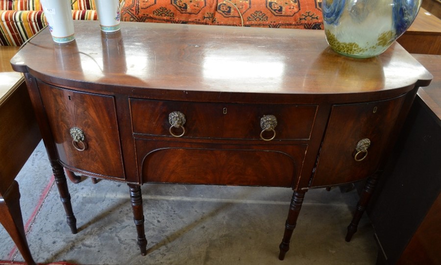 A Georgian mahogany bow front sideboard with brass lion mask handles and slender turned supports