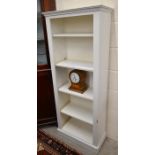 A small cream painted open bookcase with adjustable shelves