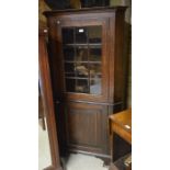 Oak floor standing corner cabinet with glazed door over panelled cupboard raised on bracket feet