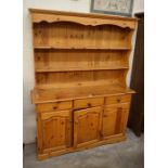 A stained pine modern kitchen dresser with a two shelf plate rack over three drawers and panelled