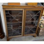A small mahogany bookcase with a pair or astragal glazed doors enclosing shelves, raised on