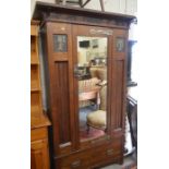 Arts and Crafts panelled oak wardrobe with mirrored door enclosing hanging space over a single