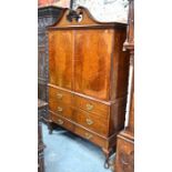 A 19th century Sheraton Revival style cabinet on stand, the broken swan neck pediment over a pair of