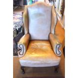 A Georgian style studded tan leather wing armchair, raised on short cabriole front legs (a/f)