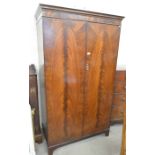 A flame mahogany wardrobe with a pair of full length cupboard doors, raised on bracket feet