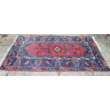 A Turkish caucasian design rug with diamond medallion on red ground within geometric navy border