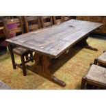A substantial rustic oak refectory style dining table, the rectangular cleated plank top raised on