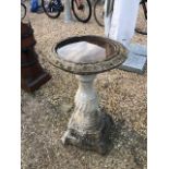 A weathered cast stone birdbath