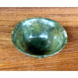 An Asian small mottled spinach-green bowl with everted rim, 8 cm diameter