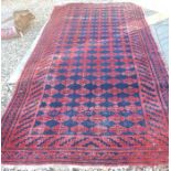 A worn Bidja kelleigh rug with six rows of repeating guls on navy ground within geometric borders