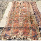 An antique very worn Caucasian runner with stylised motif on rust ground within a dark double