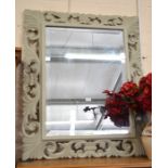 A large bevelled edge mirror in grey painted foliate frame