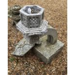 A Japanese stone garden lantern raised with a curved arm on a heavy plinth base, in sections