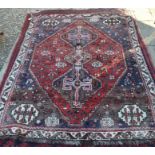 A Persian Shiraz rug, the three central linked diamond medallions on red ground with flora and fauna