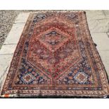 A Persian Shiraz rug with central navy lozenge medallion on red ground with geometric motifs