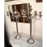 A pair of tall silvered metal classical column five-branch candelabra