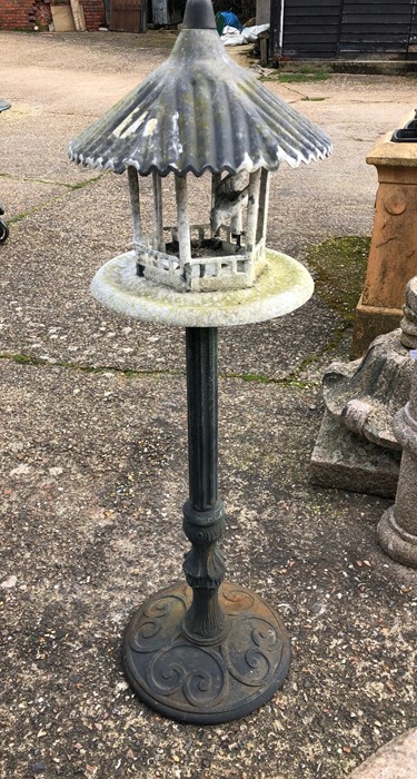 A weathered Asian style cast alloy bird feeder raised on a column